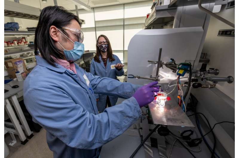 uosong Zeng, a postdoctoral scholar, and Francesca Toma, a staff scientist, both in Berkeley Lab's Chemical Sciences Division, test an artificial photosynthesis device made of gallium nitride. Rather than degrading over time, which is typical for devices that turn water and light into hydrogen fuel, Toma and Zeng discovered that this device improves. Credit: Thor Swift/Berkeley Lab